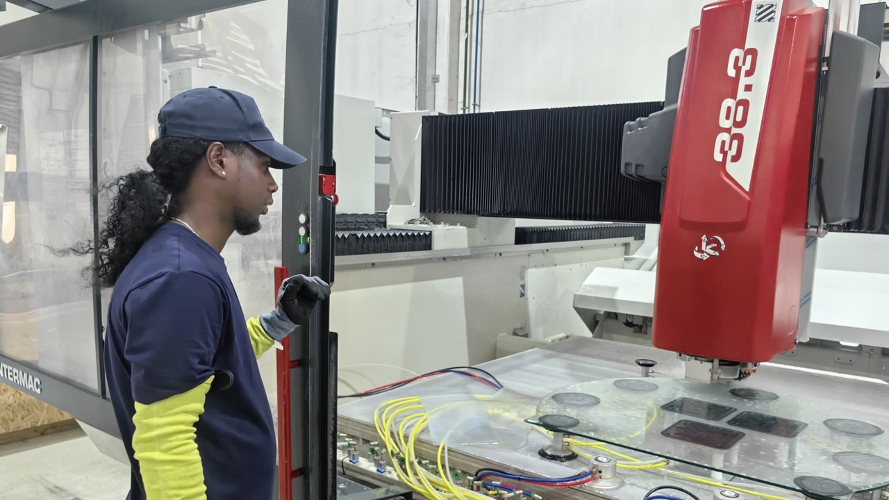 Un opérateur contrôle avec précision une machine de découpe numérique Intermac, utilisée pour façonner le verre avec une exactitude millimétrique.